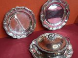 trois plats en argent posés sur une table recouverte d'une nappe rouge