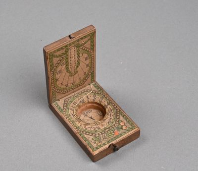 boîte en bois contenant une boussole, posée sur une surface grise