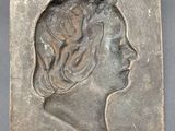 a close up of a metal plaque with a woman ' s face