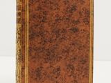 an old book with gold trimming and a brown cover