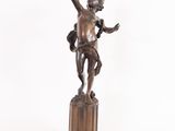 bronze statue of a boy holding a bird on a pedestal