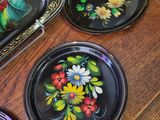 three plates with flowers painted on them sitting on a table