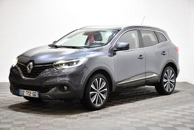 Une voiture grise est garée sur un sol à damier dans une pièce.