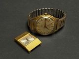 une montre en or et une montre carrée sur un fond noir