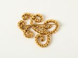 a close up of a gold brooch on a white surface