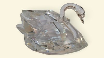 figurine de cygne en cristal posée sur une surface blanche, avec un fond blanc