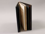 an open book sitting on top of a white table next to a white wall