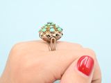 an image of a woman ' s hand holding a gold ring with turquoise stones
