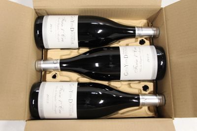 three bottles of wine are in a cardboard box on a table