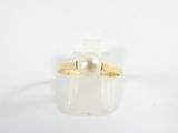 a close up of a ring with a pearl in it on a white surface
