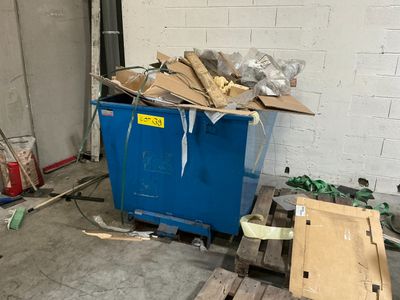a blue dumpster sitting in a garage next to pallets of wood