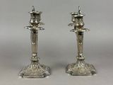 pair of antique silver candlesticks on stands on a grey background