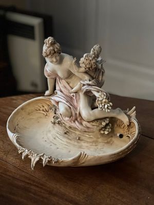 une figurine posée sur un bol, lui-même posé sur une table