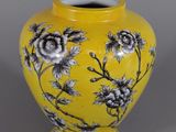 un vase jaune orné de fleurs noires et blanches