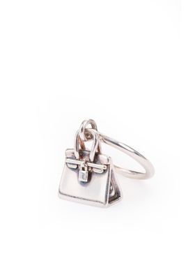 un gros plan d'une bague en argent sur laquelle est représenté un sac à main