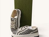 une paire de baskets noires et blanches avec une boîte verte sur fond blanc