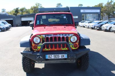 a red jeep parked in a parking lot with other cars