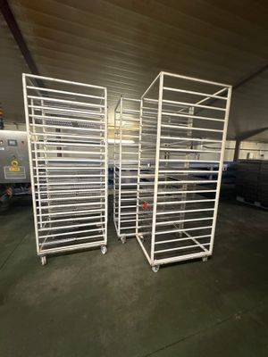 trois rayonnages remplis de denrées alimentaires se trouvent dans un entrepôt, avec un camion en arrière-plan