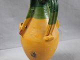 a yellow and green vase sitting on a white surface