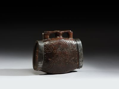 un vase marron posé sur une table blanche, près d'un mur noir