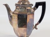 an antique silver teapot with a black handle on a white background