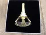 a gold plated brooch with a brush inside of it