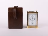 an image of a small clock sitting next to a leather case