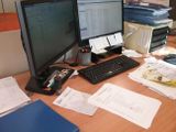 un bureau sur lequel se trouvent deux écrans d'ordinateur et des papiers