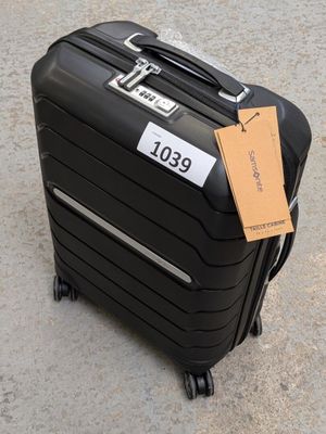 a black suitcase with a tag on it sitting on the ground
