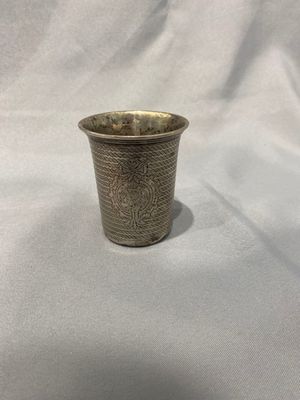 une image représentant une coupe en argent posée sur un tissu blanc