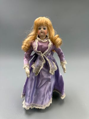 poupée en porcelaine représentant une femme vêtue d'une robe violette bordée de dentelle blanche