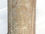 an old metal object with a design on it on a white surface
