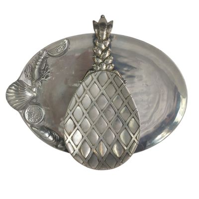 a silver plate with a pineapple on top of it