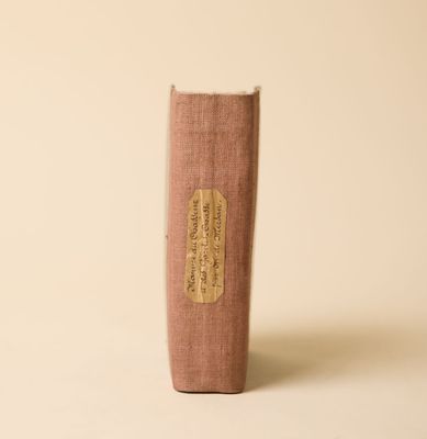 un vieux livre posé sur une table à côté d'un mur blanc