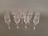 twelve wine glasses lined up in a row on a table