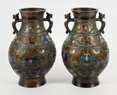une paire de vases anciens posés sur une surface blanche