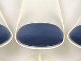 four white tulip chairs with blue cushions in a circle