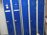 two blue lockers in a room with bags on the floor