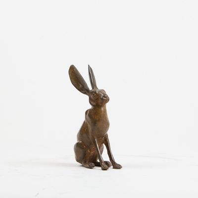 une statue en bronze représentant un lapin assis sur une surface blanche
