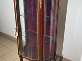 a display cabinet with a glass door in the corner of a room