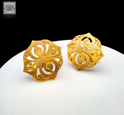 paire de boucles d'oreilles plaquées or, avec un motif en filigrane sur fond blanc