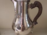 une cafetière en argent posée sur une étagère à côté d'un vase