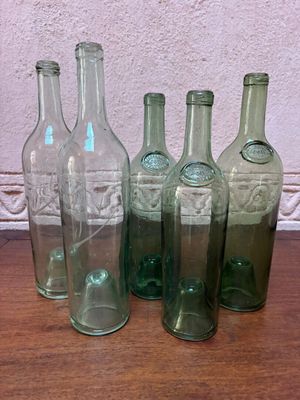Six bouteilles en verre vert sont alignées sur une table en bois.
