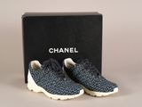 une paire de baskets bleues et blanches devant une boîte noire