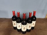 six bottles of red wine are lined up on a wooden table
