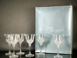 six verres à vin posés sur une table, à côté d'une boîte