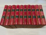 six livres rouges sont empilés les uns sur les autres sur une table