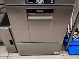 stainless steel dishwasher in a commercial kitchen with blue bins in the background