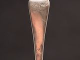 close up of a silver spoon with a silver handle on a black background