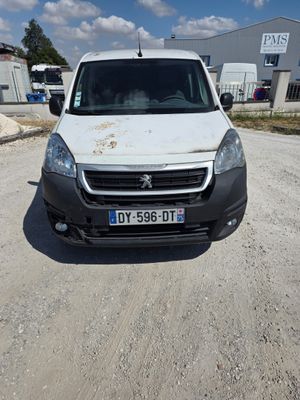 La camionnette blanche est garée sur le chemin de terre du parking.
